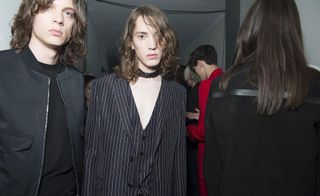 2 models in dark clothing looking into the camera in a crowded room