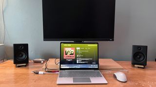 PC-Lautsprecher auf einem Schreibtisch mit Laptop und Monitor.