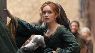 Alicent grabs hold of a wall in the street