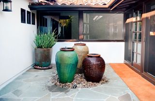 mediterranean patio with three vase style water fountains