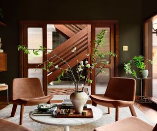 A mid-century modern library with brown chairs and floor-to-ceiling bookshelves