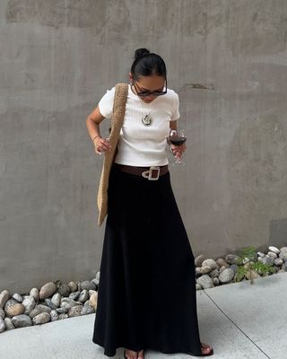 @dawn.tan wearing a black skirt, flip-flops, t-shirt and raffia tote