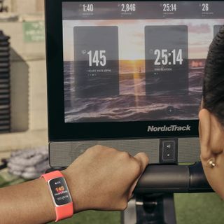 Person wearing Fitbit Charge 6 on NordicTrack rowing machine, the heart rate on the watch is mirrored on the screen