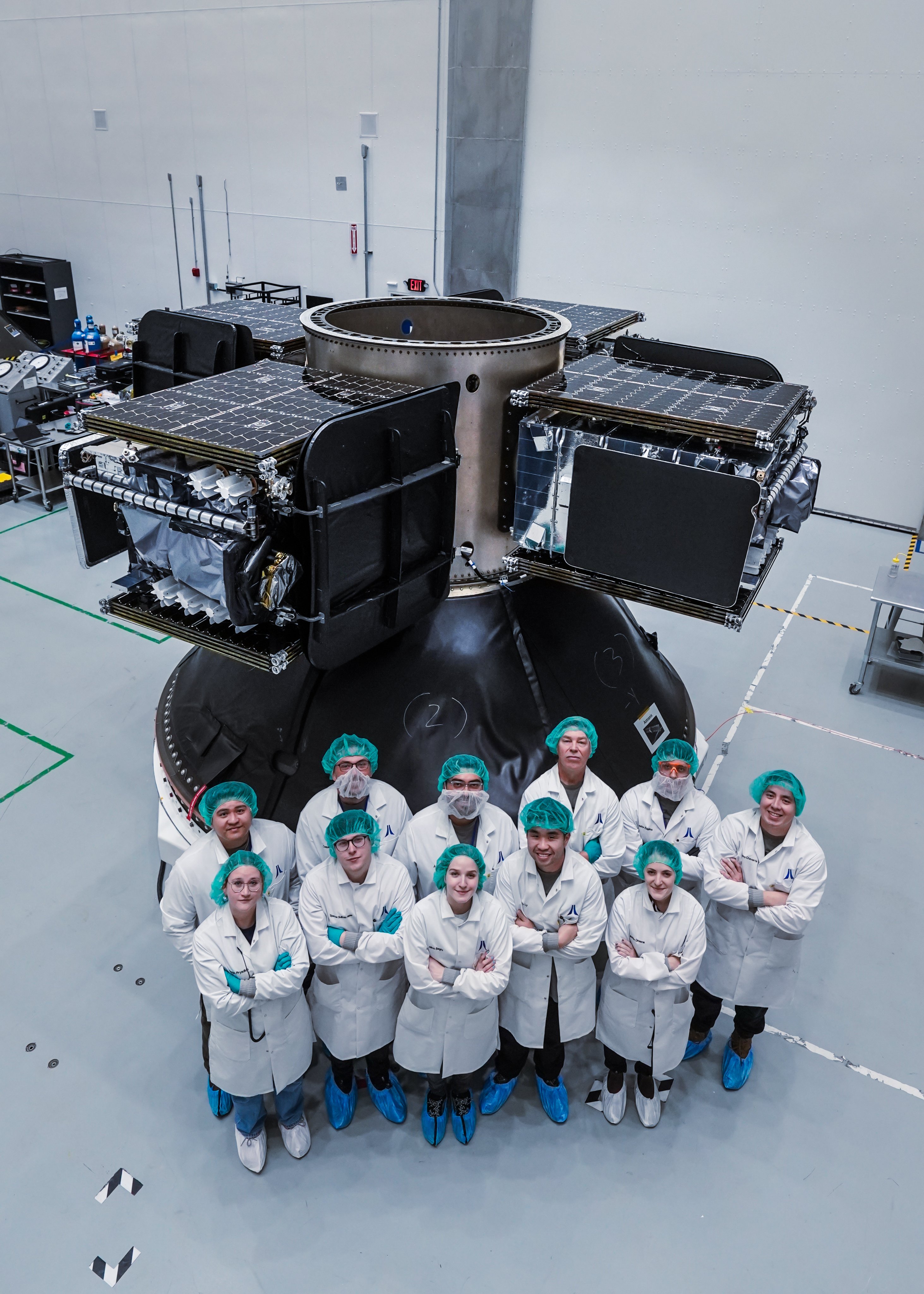 Astranis engineers pose with four MicroGEO communications satellites.