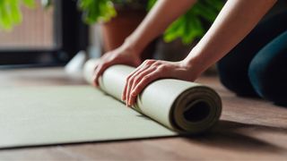 Woman's hands rolling up yoga mat