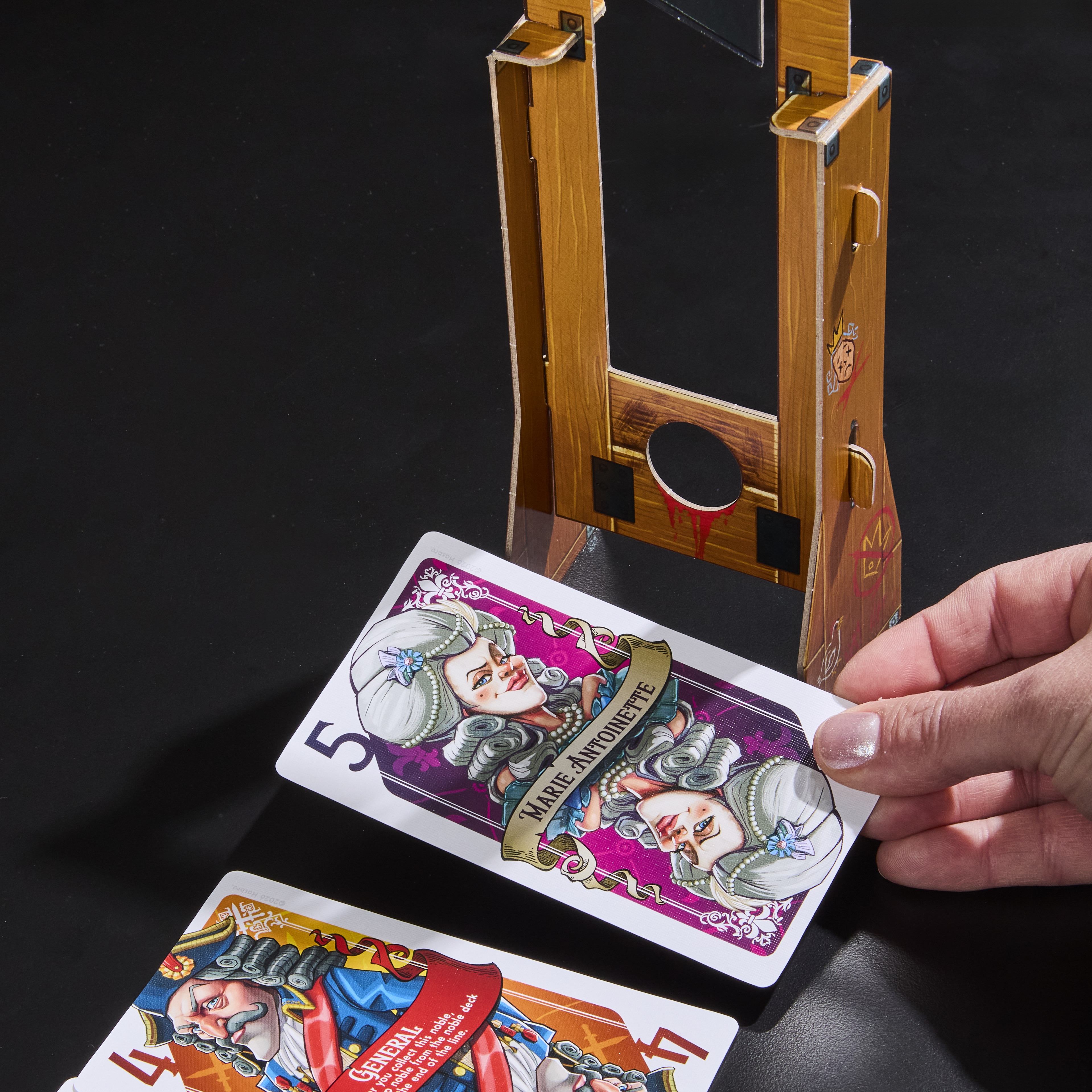 Guillotine box, cards, and prop on a dark background