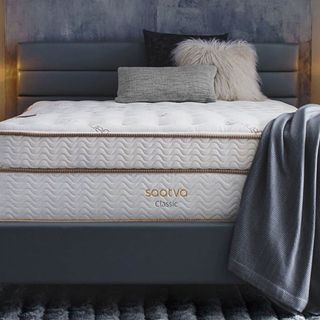 Saatva Classic mattress with a gray throw against a gray wall.