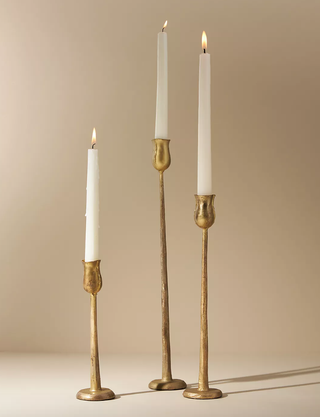 three gold candlesticks holding white candles