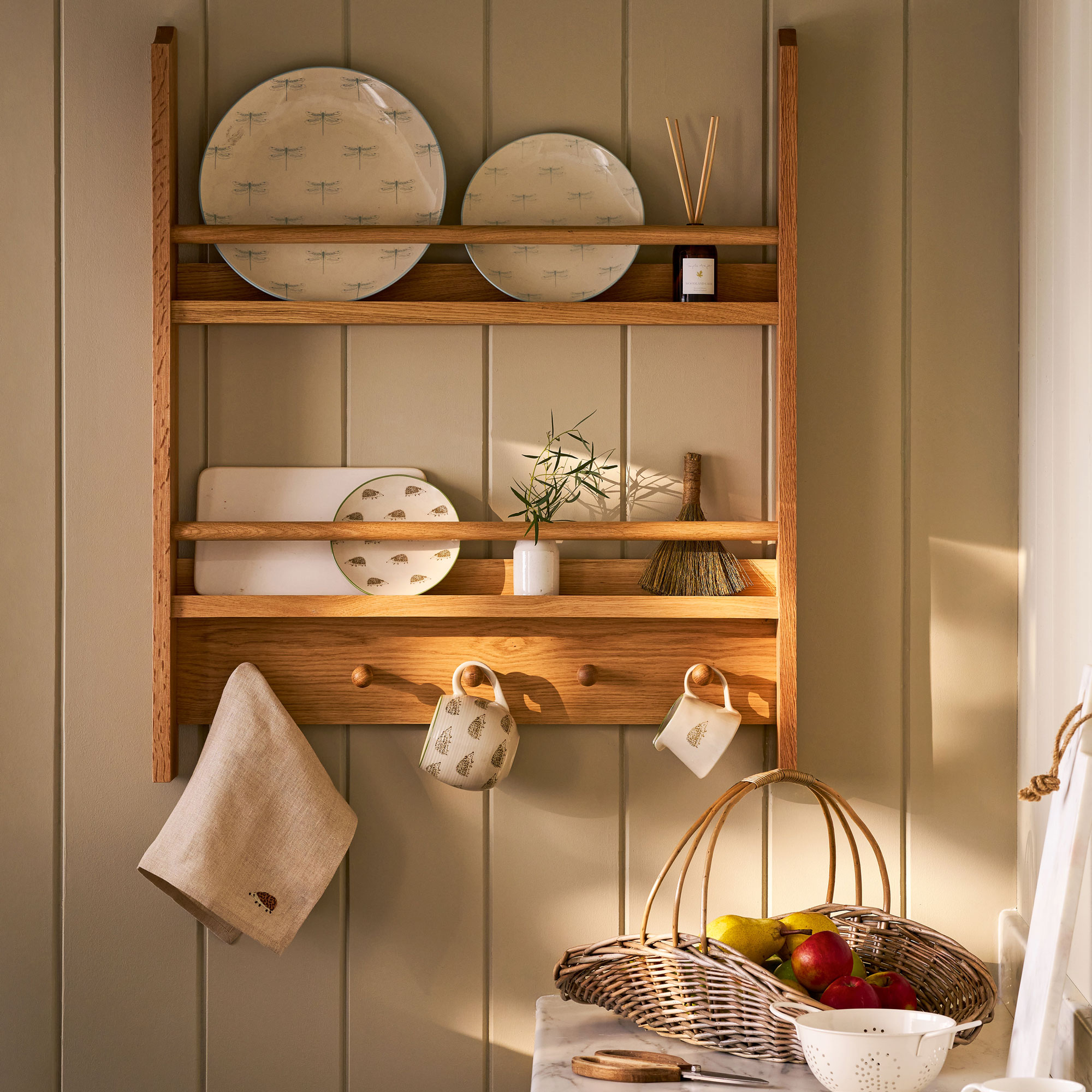 Wooden dish rack with patterned ceramic plates and mugs hanging from it