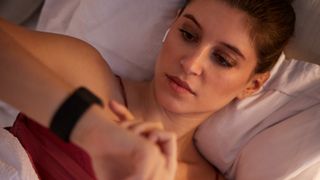 Woman checking smartwatch in bed