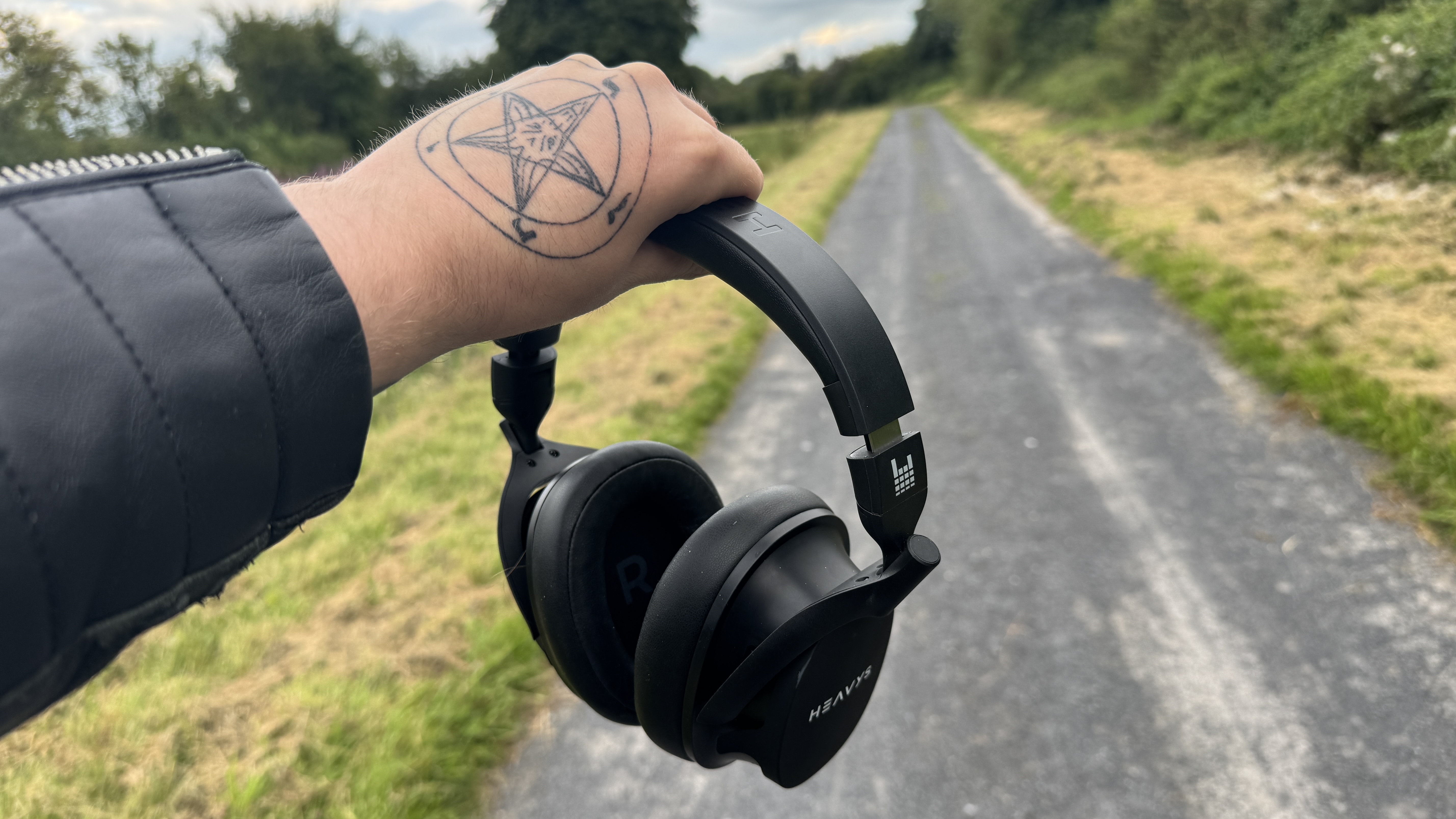 A woman holding the Heavys headphones outside