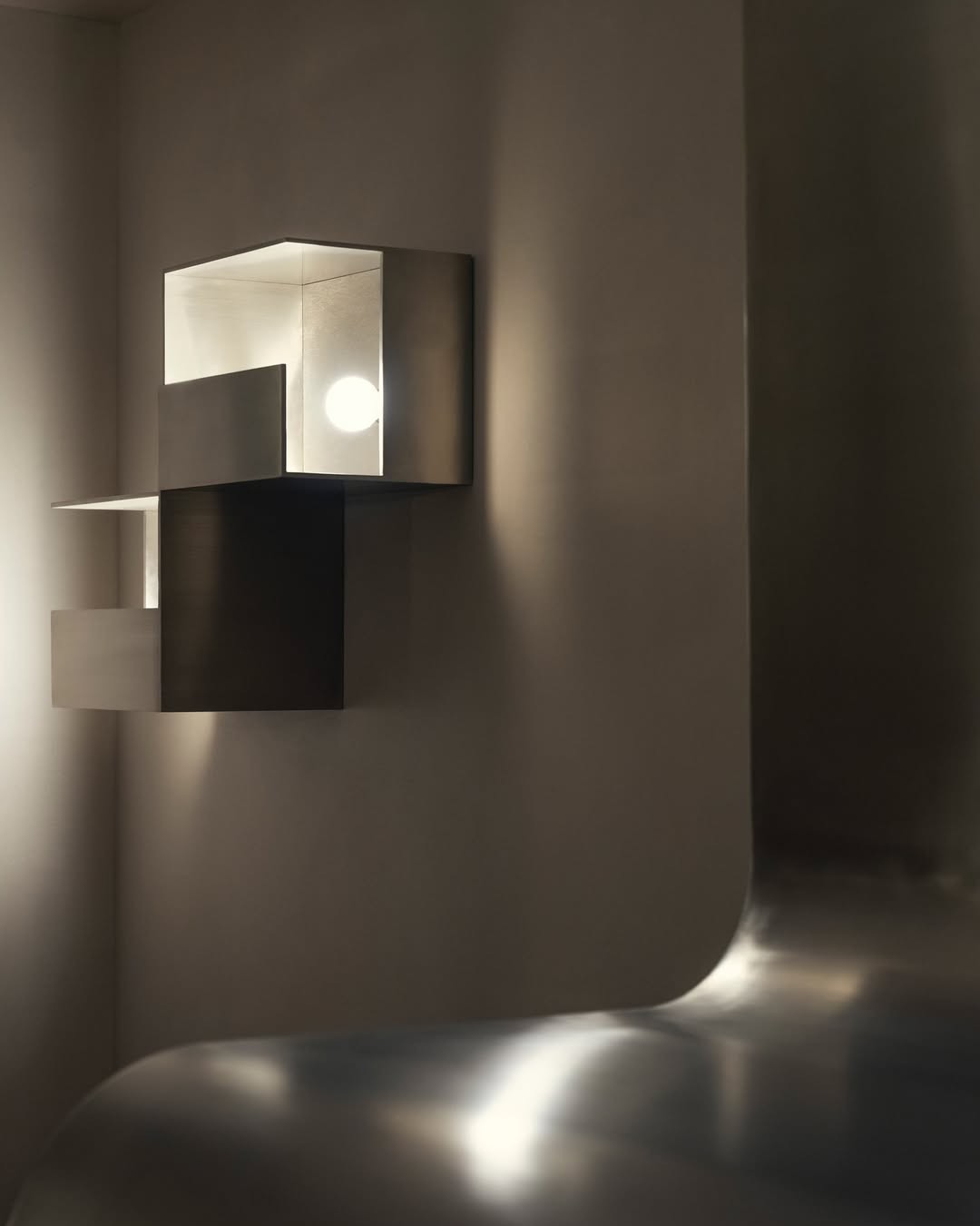 A chrome-clad apartment, featuring atmospheric cold lighting, brushed steel surfaces, and a pared back design scheme.