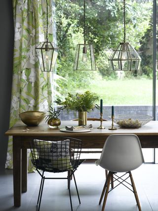 Glass cage Pooky lights over a dining area in a modern kitchen dining table with candlesticks and mix matched chairs