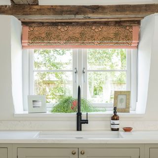 sink with black tap looking out onto garden, green and pink curtain