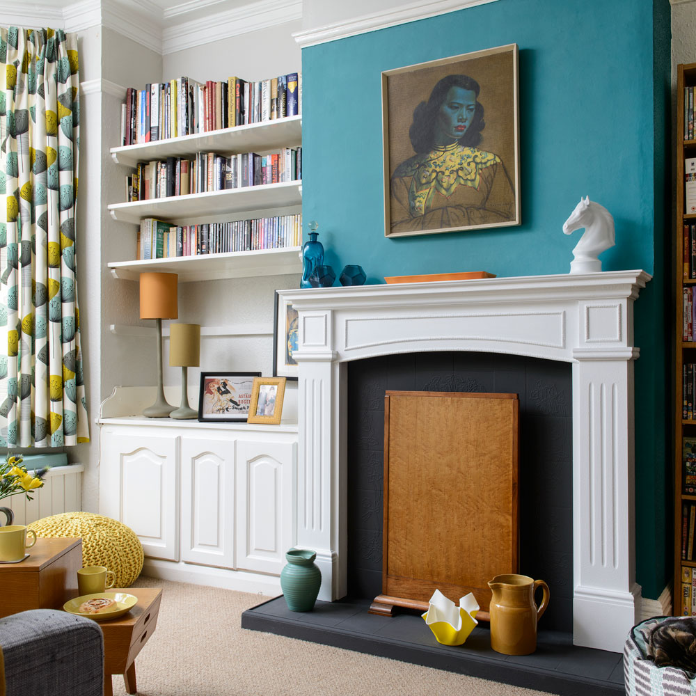 blue wall riving room with book shelf fireplace and patterned curtains