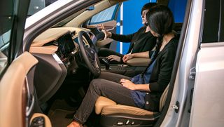 Two women sat in a n opened door car, car interior, blue wall background