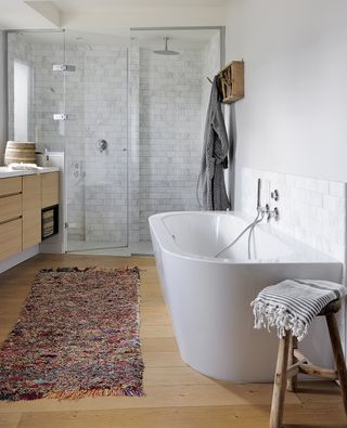 white bathroom with wood stool next to the bath