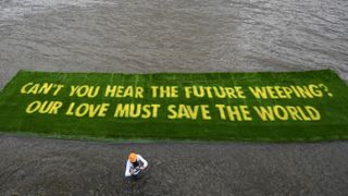 A giant banner grown on a carpet of living grass tells governments to ‘act now’ in the lead-up to COP26, on 25 June 2021