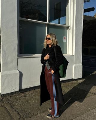 Fashion influencer @lucywilliams02 wearing an on-trend winter outfit in London with sporty burgundy Adidas pants.