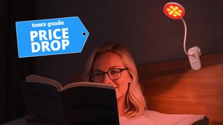 A blonde woman wearing glasses reading in bed with red light clip