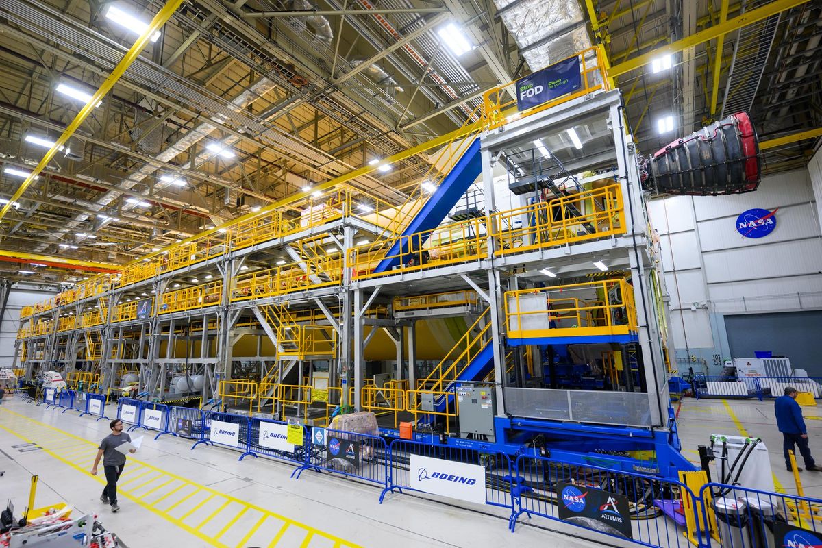 A technician walks by a stand where the RS-25 engine is being mounted on the core stage of the Space Launch System rocket, which will power the Artemis 2 mission to the moon.