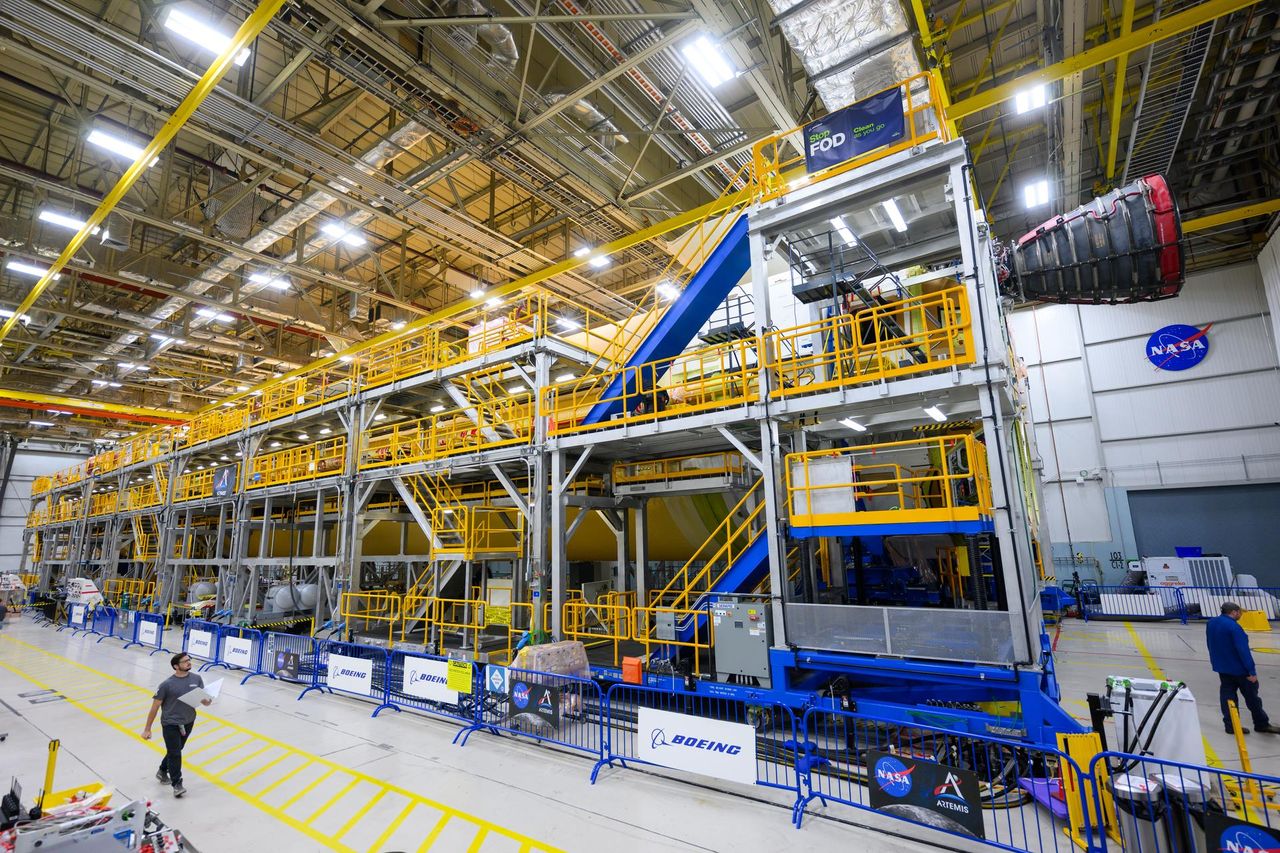 A technician walks by a stand where the RS-25 engine is being mounted on the core stage of the Space Launch System rocket, which will power the Artemis 2 mission to the moon.