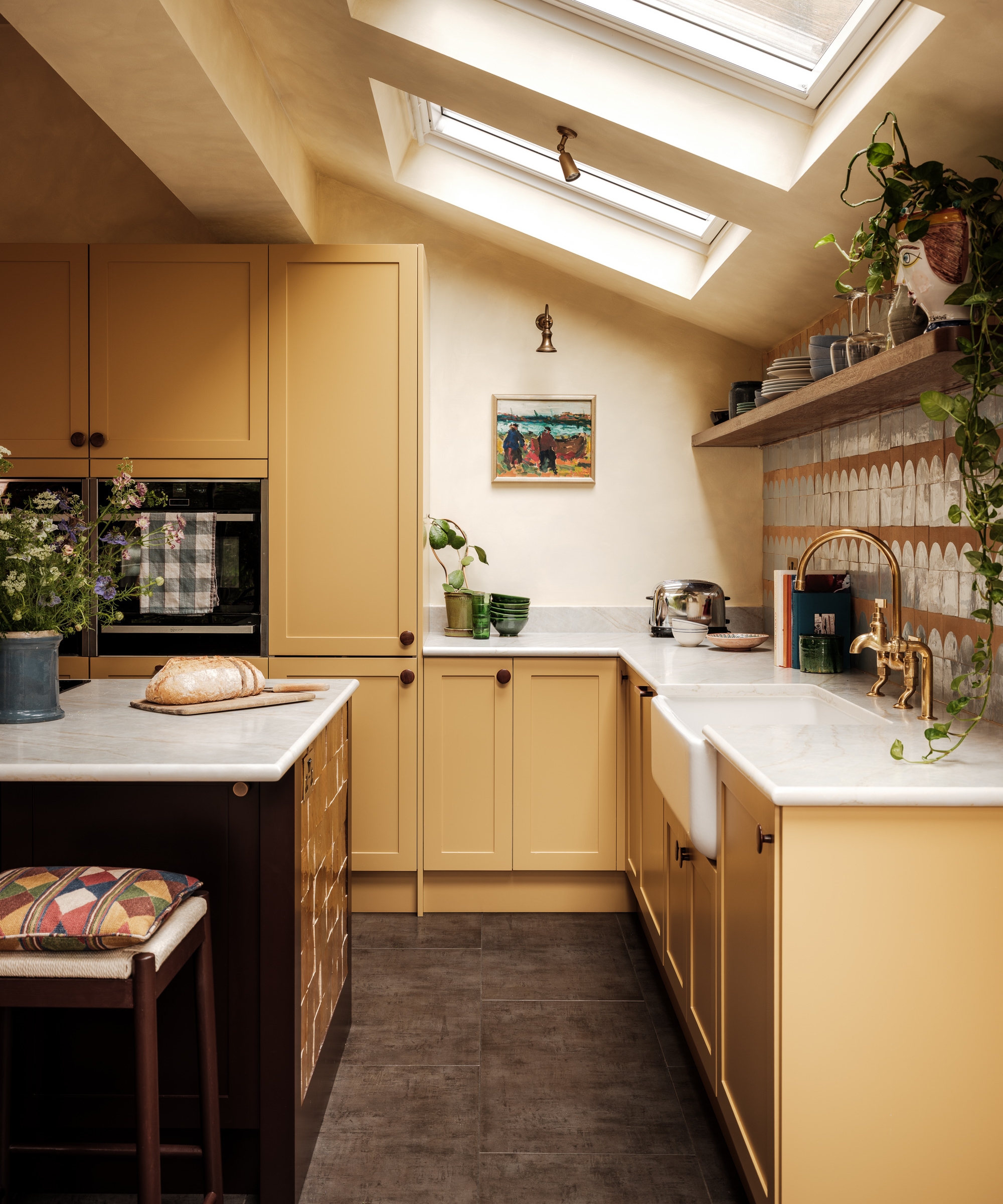 A mustard yellow kitchen with a pitched roof, white countertops, and a dark wood island