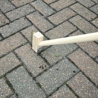 Newman and Cole Long Handle Weed Brush sweeping away weeds from patio driveway