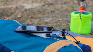 Battery pack attached to phone sitting on top of camping bag