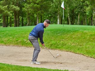 Barry Plummer hitting a bunker shot from a greenside bunker with a close pin