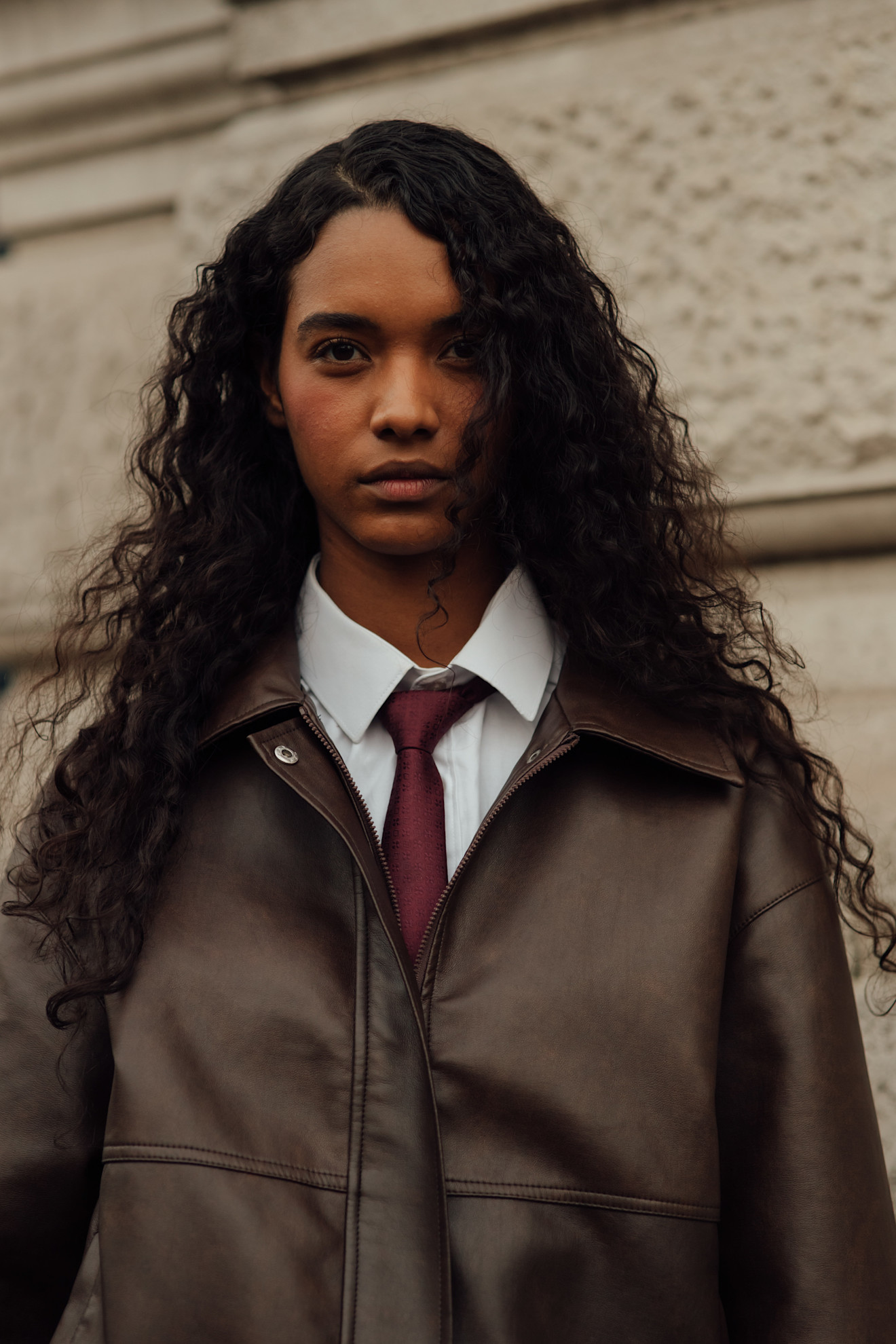 A woman at Paris Fashion Week AW26 with long natural curls and a side parting