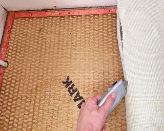 cutting the side of a piece of rolled back carpet during Carpet removal