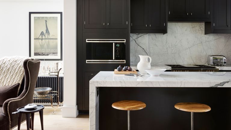 Grey kitchen ideas with marble backsplash and worktop, dark grey cabinetry and wooden bar stools