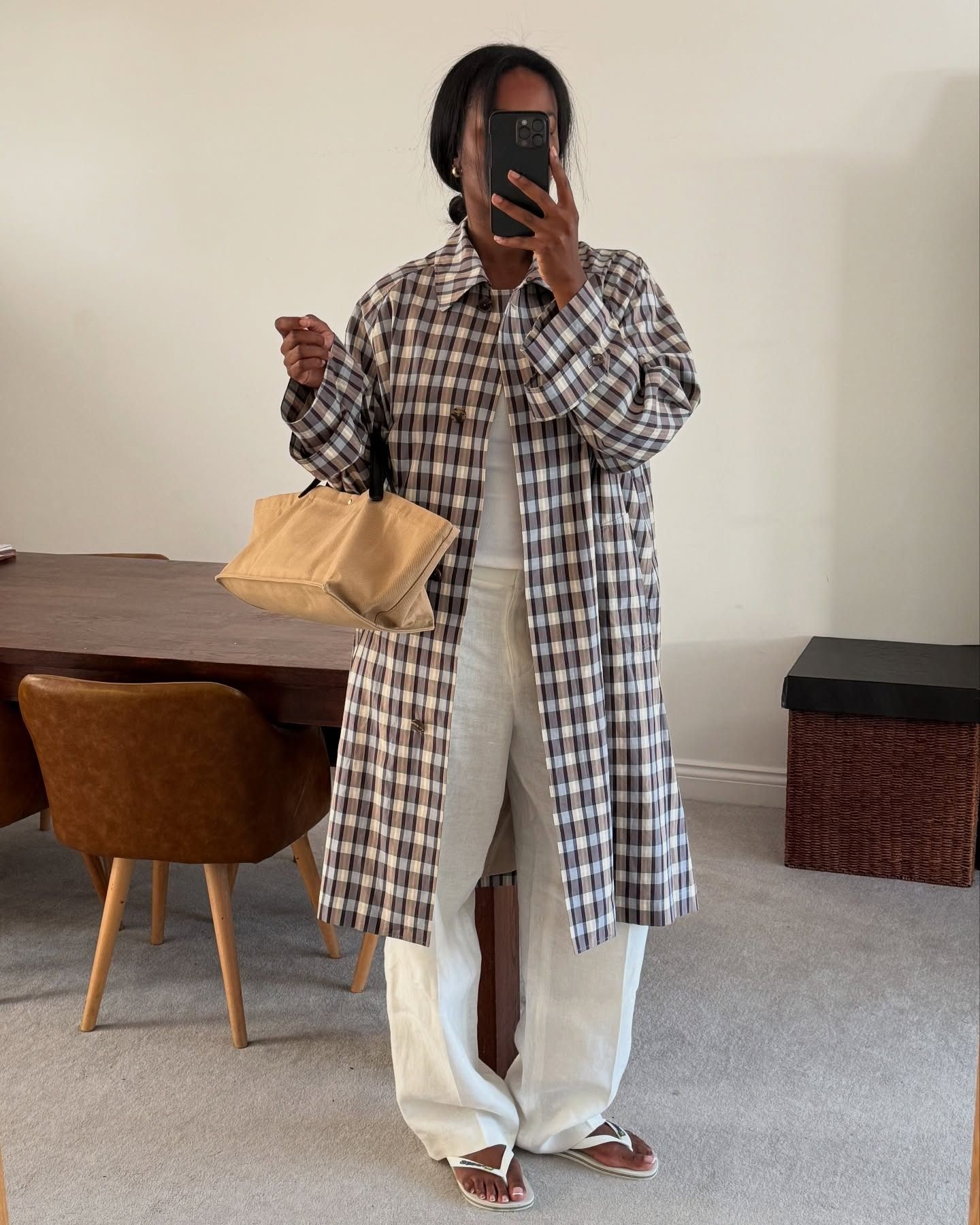 Influencer Marilyn NK wearing a checked trench coat and white pants with flip-flops