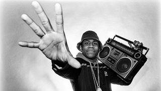 Photo of hip-hop fan carrying boombox and holding up hand to the camera