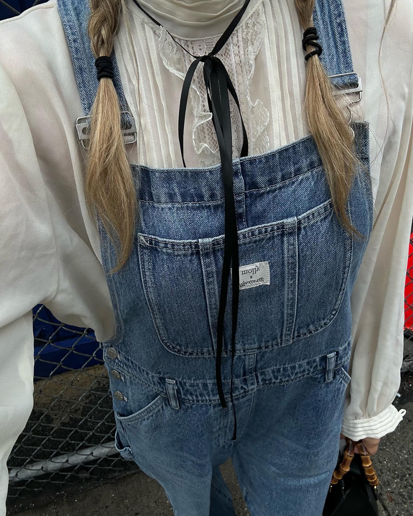 An image of @thepouf wearing denim dungarees with a lace blouse, one of the biggest spring 2026 denim trends.