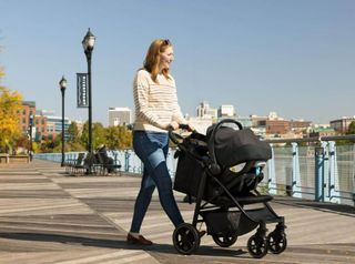 A smiling woman pushes the Graco EeZefold pushchair