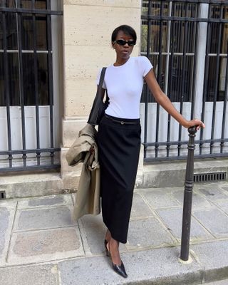 Woman wearing a white tee and long black skirt.