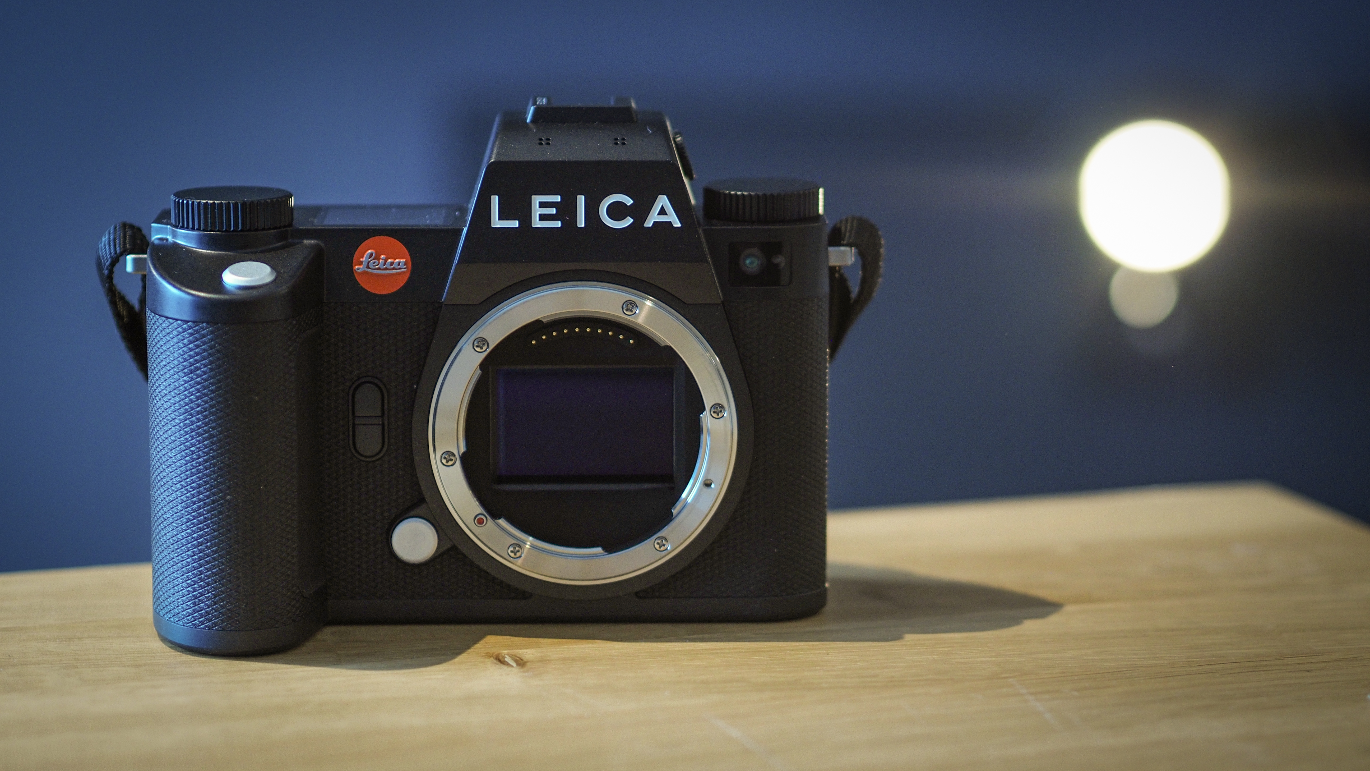 Leica SL3 camera on a wooden surface against a blue background