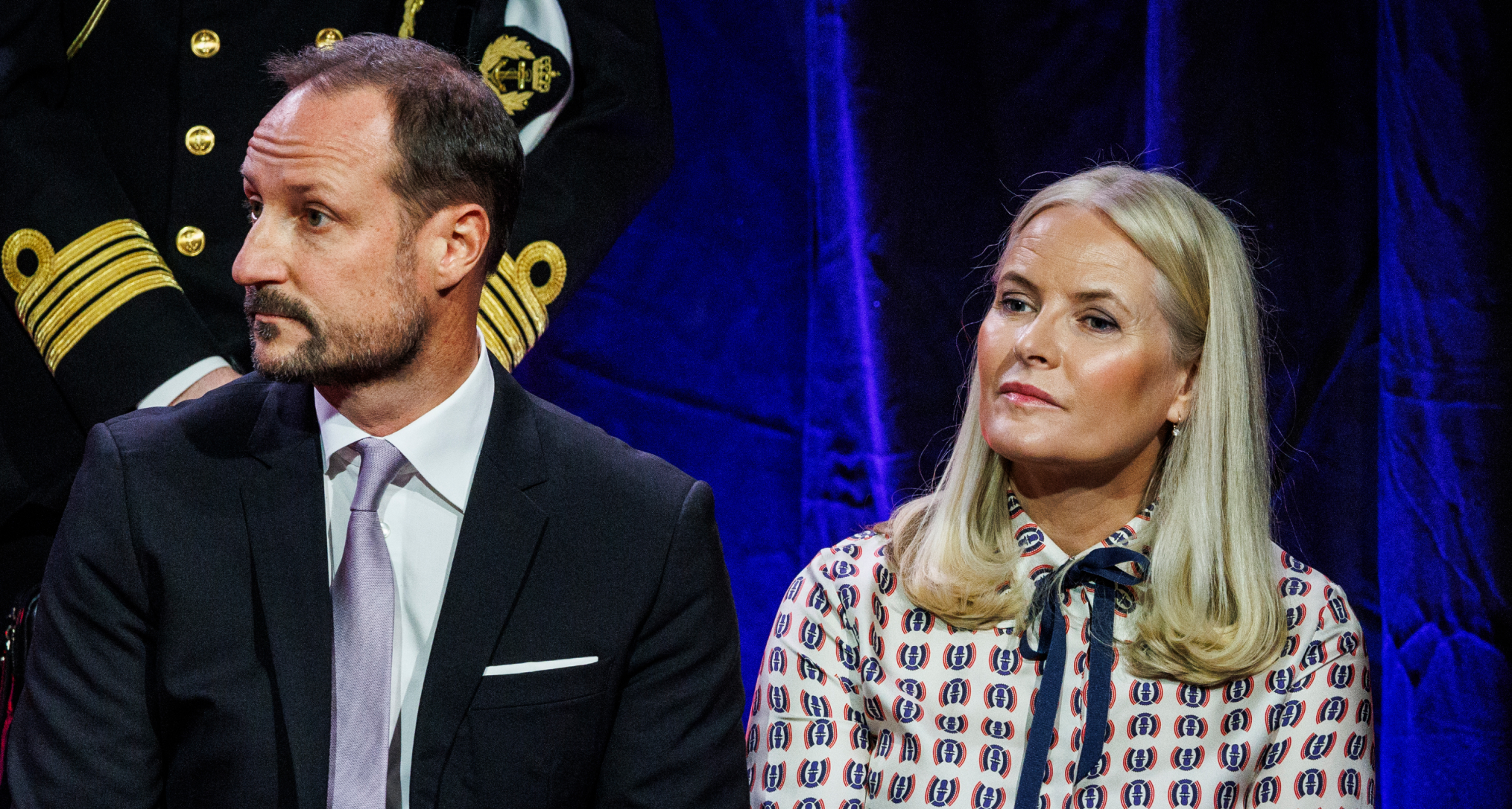 Crown Princess Mette-Marit sitting next to Crown Prince Haakon on a stage