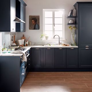 blue kitchen with white worktops and window