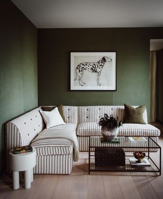 Green wallpaper, striped L shape sofa, glass coffee table