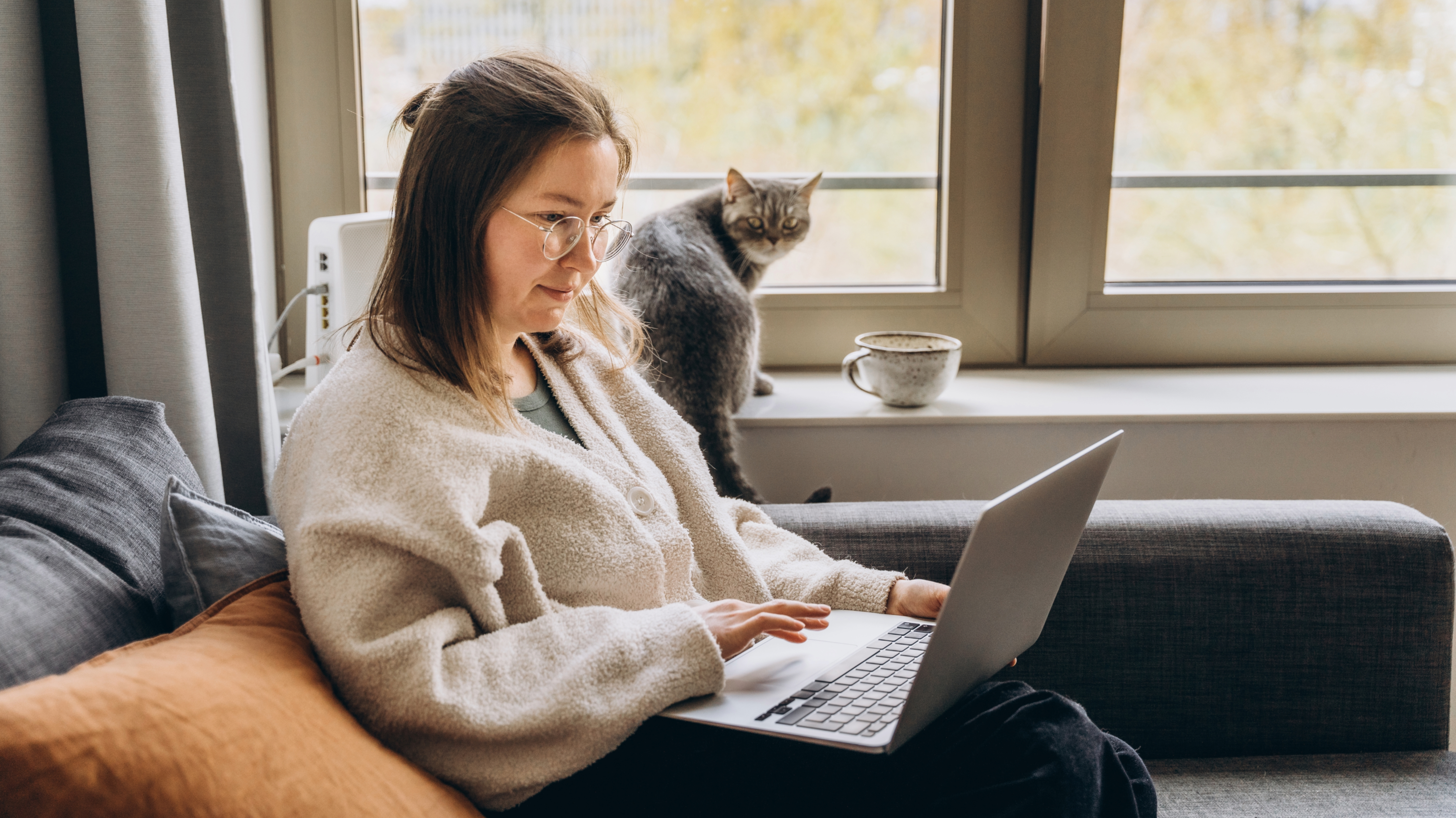 Cat watching woman use laptop