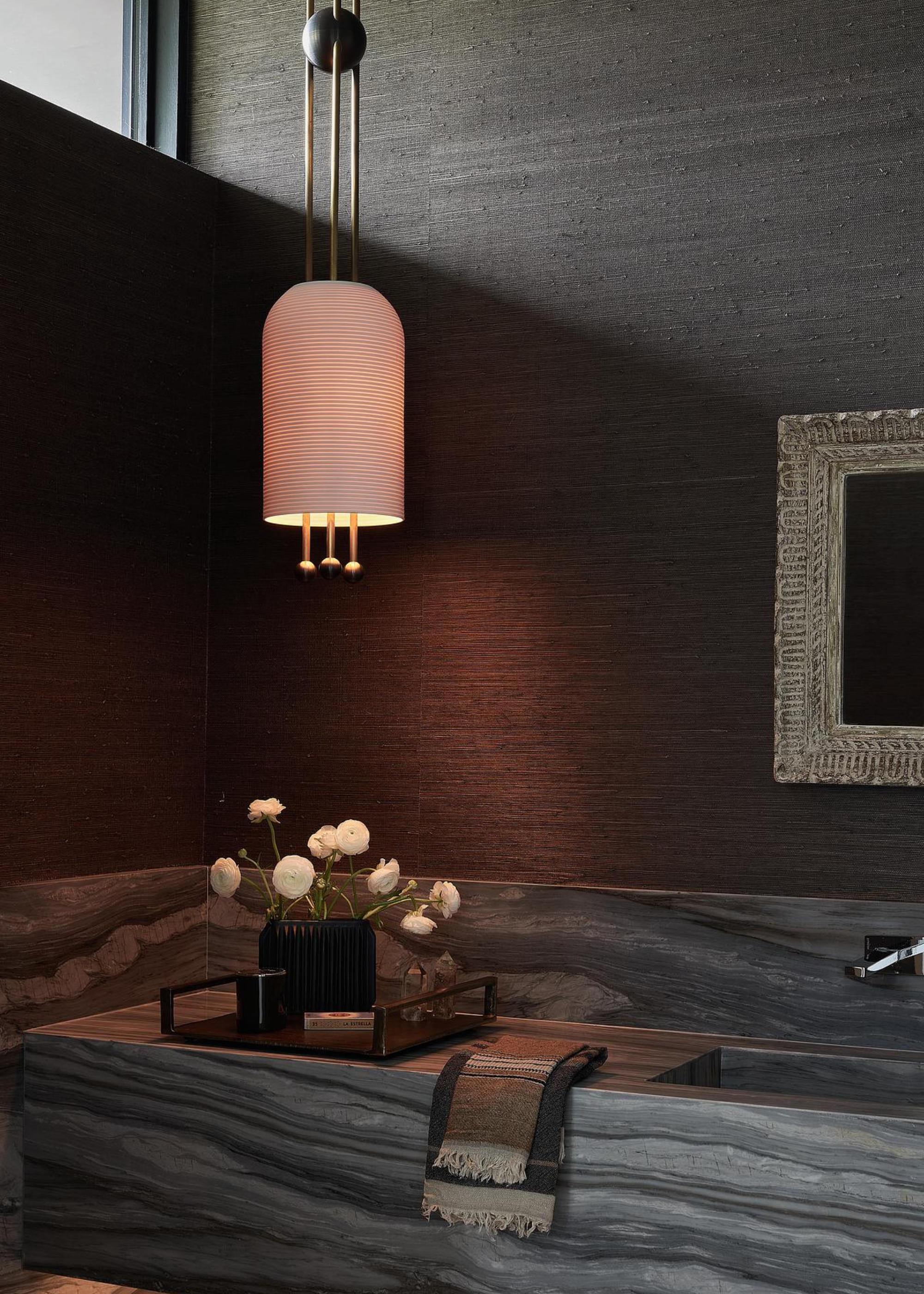 a marble bathroom countertop with a pendant light hanging above it