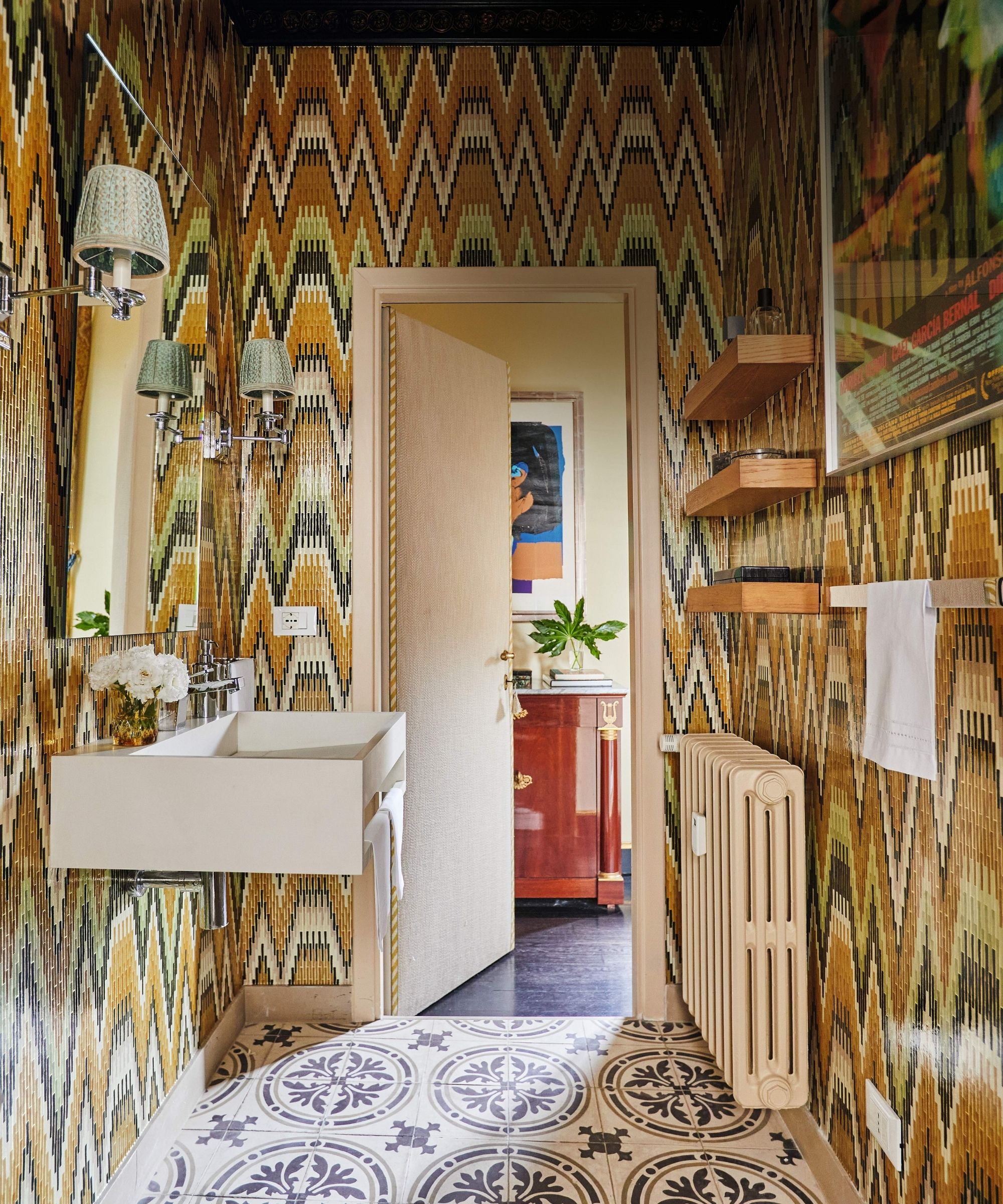 a yellow missoni style wallpapered powder room with modern white sink and patterned floor tile
