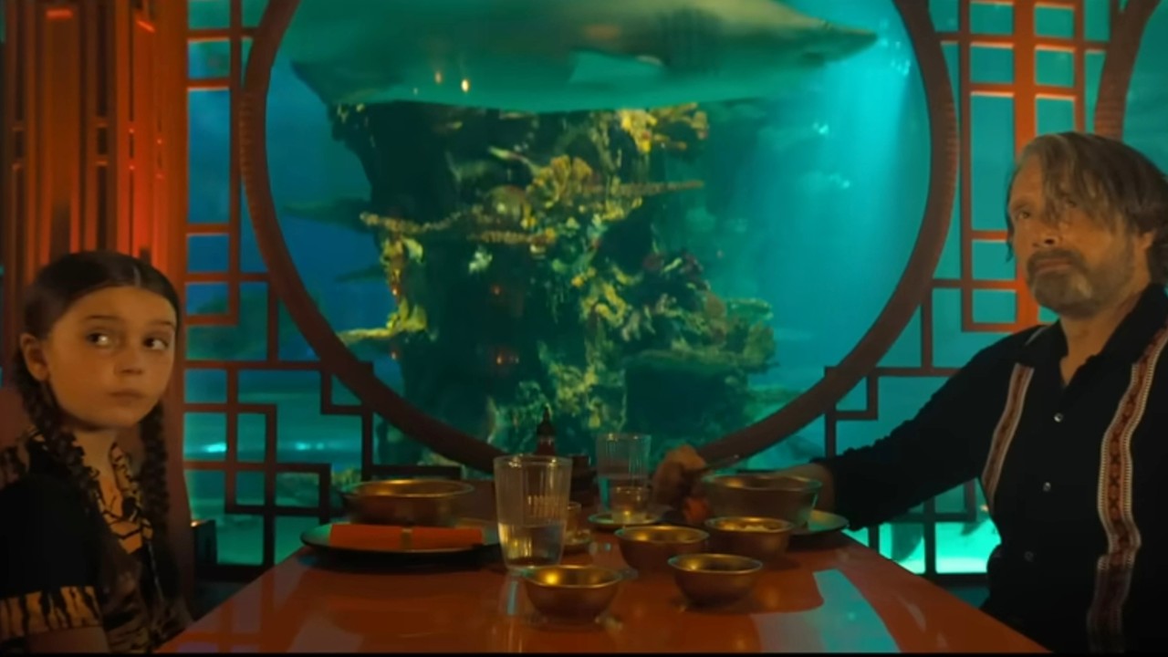 ダストバニーのテーブルに座るソフィー・スローンとマッツ・ミケルセン。