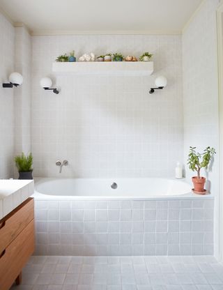 White bathroom with tub, wall tiles and open shelving