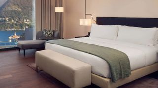 The Hilton Mattress on a bed base dressed in Hilton bedding and pillows, in a Hilton hotel room with a view overlooking the sea