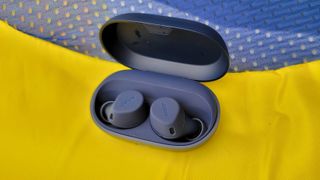The Jabra Elite 7 Active laid on a yellow and navy blue backdrop