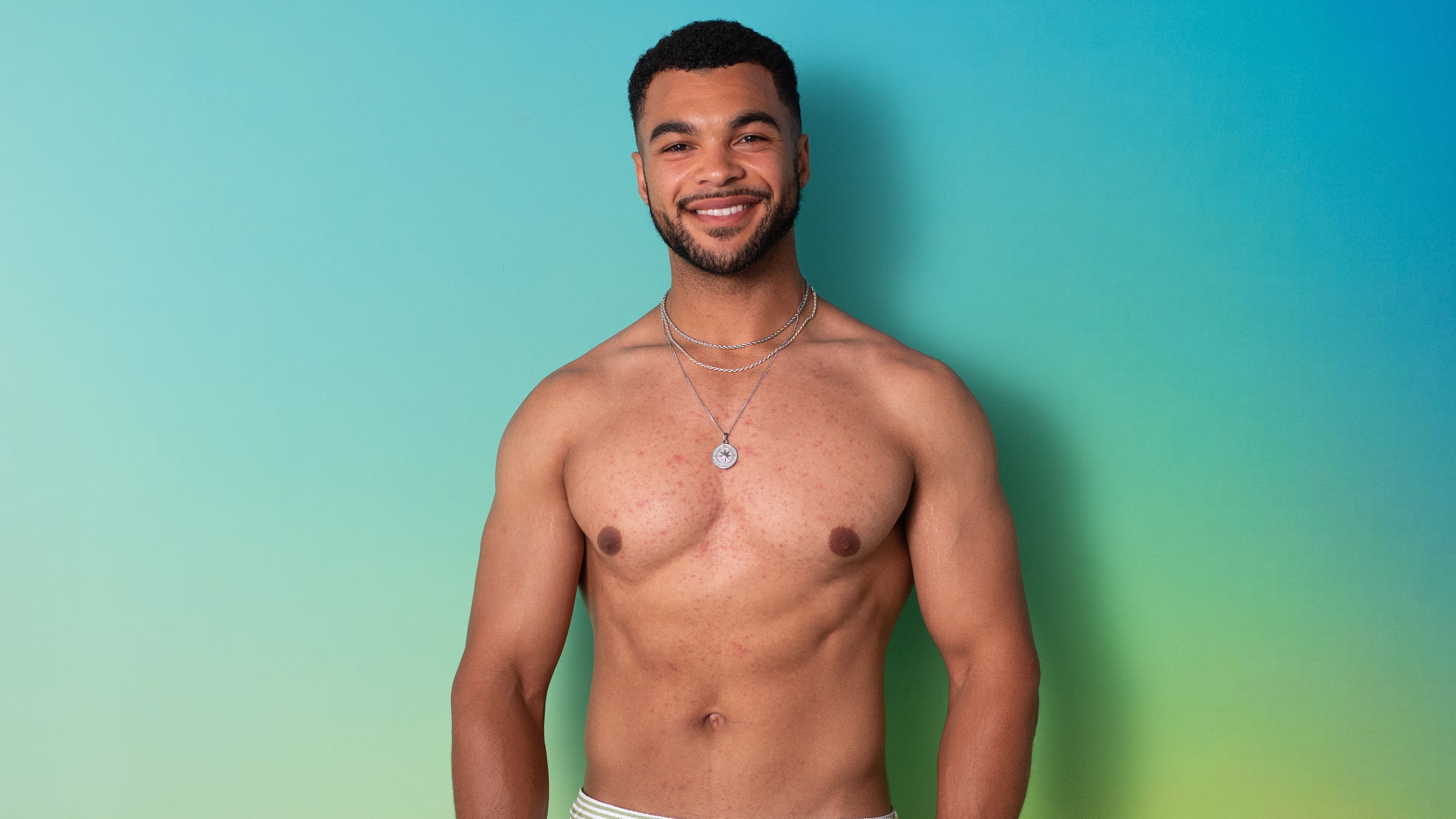 Jamie standing in swimwear in front of a green background.